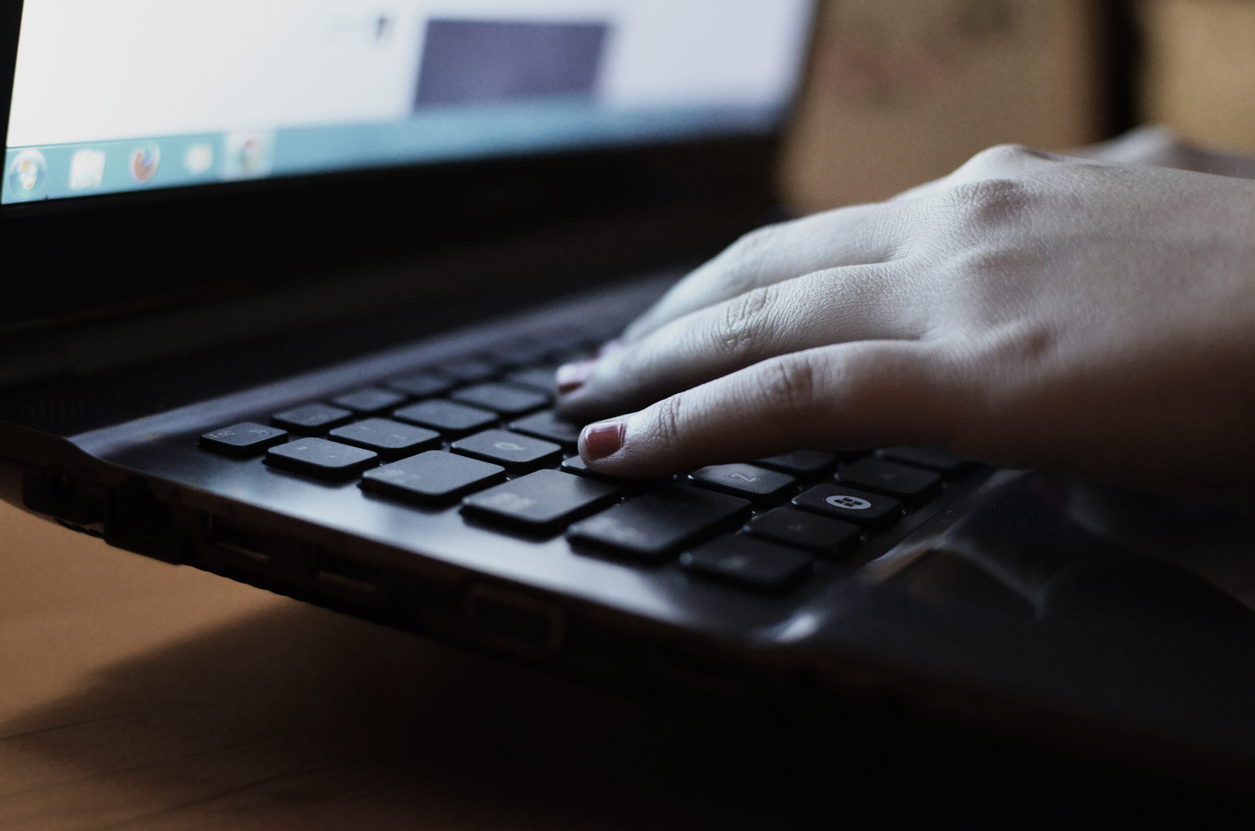 Hands typing on a laptop with a notebook during the affiliate blog writing workflow