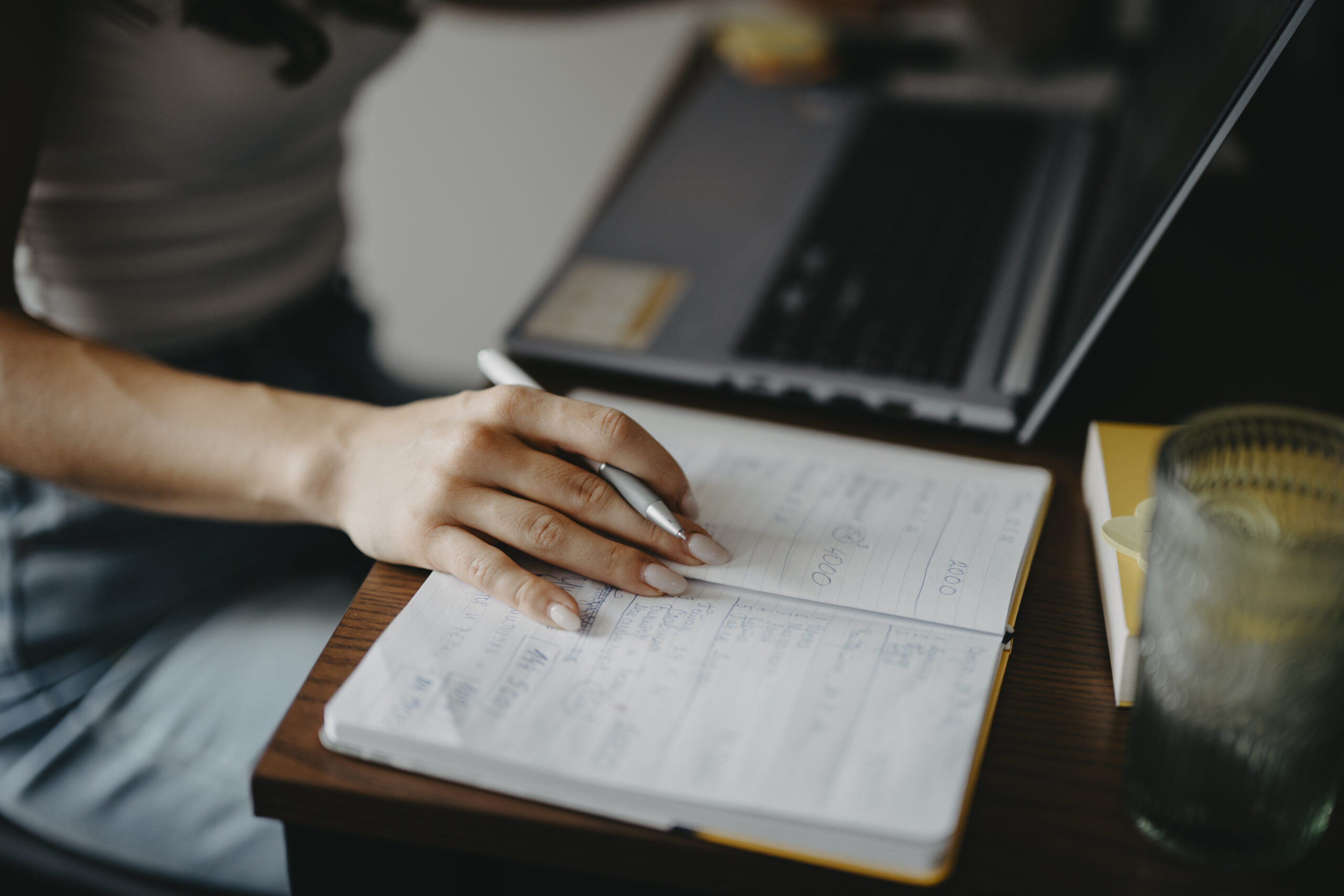 Person writing notes at a desk while drafting an affiliate marketing article