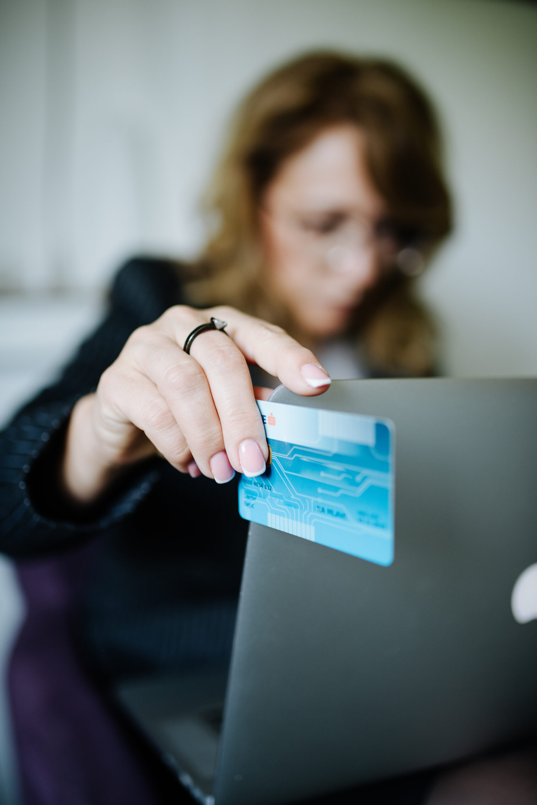 Woman holding credit card while shopping on laptop — commercial search intent means buyers, not browsers