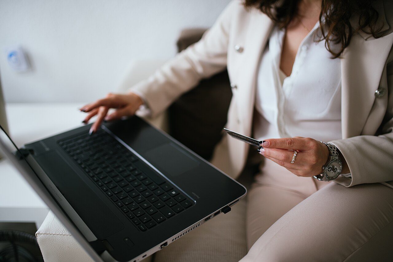 A business professional shopping online from a home workspace with a laptop and credit card