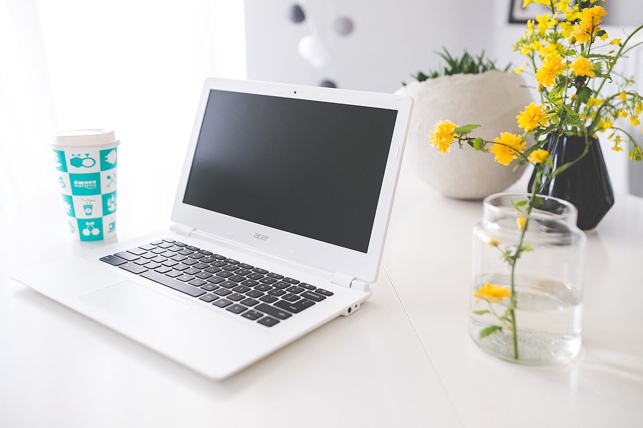 Laptop, notebook and coffee on a desk.
