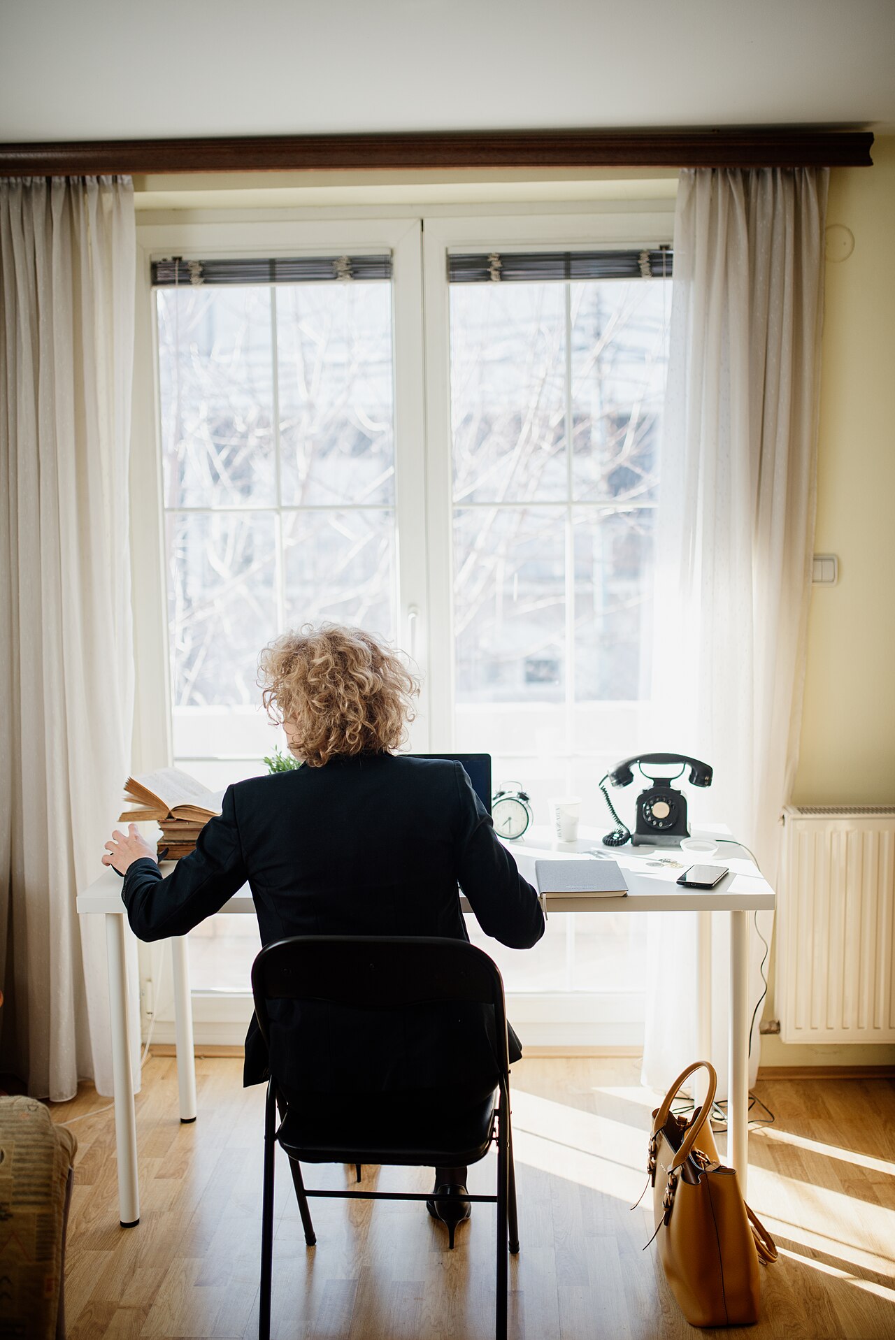 Person working at a desk with a laptop near a window