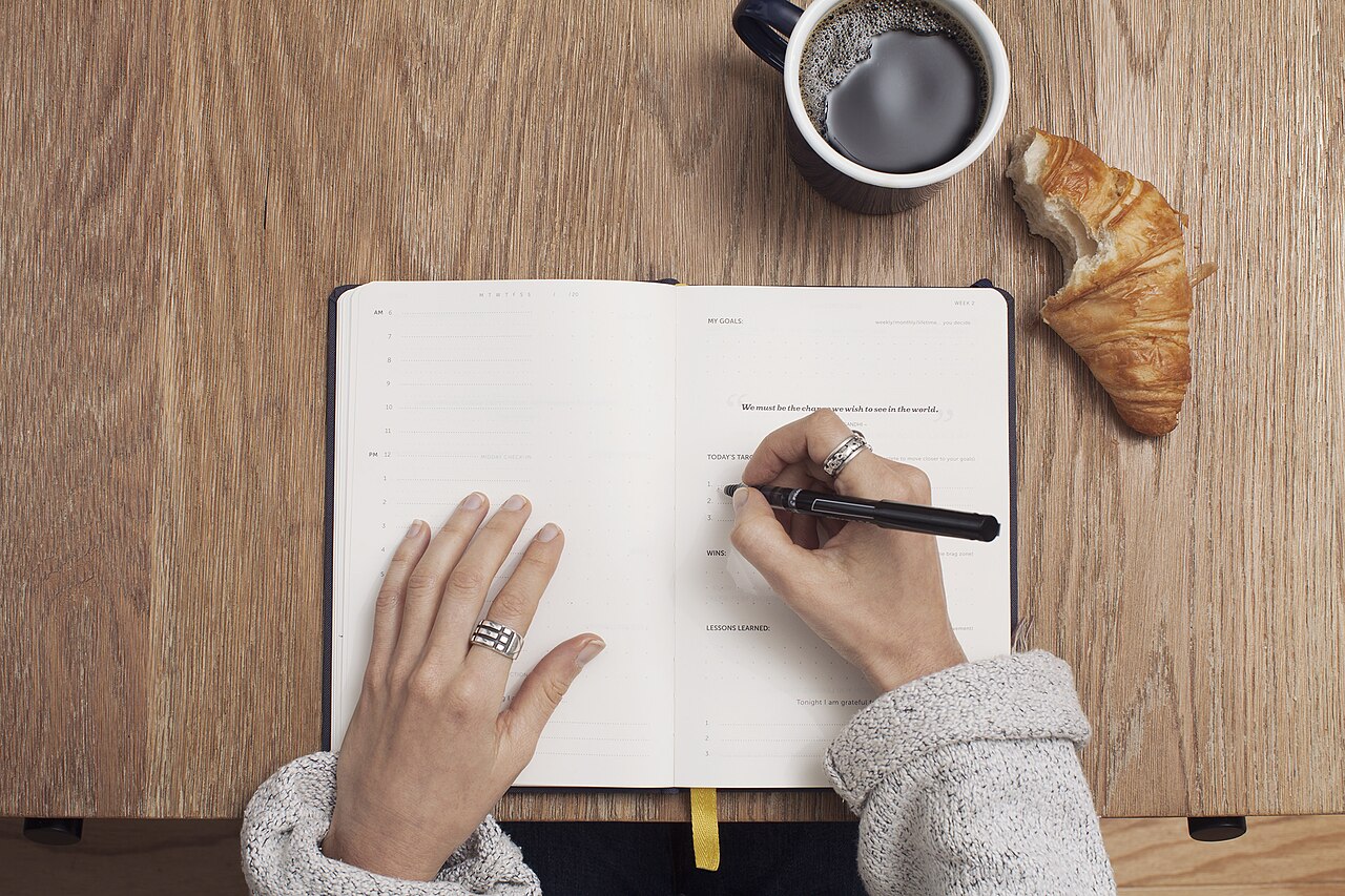 Writing notes in a journal next to a laptop