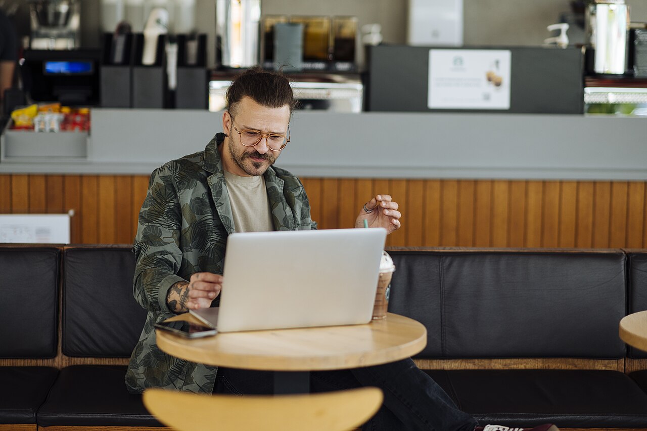 Man working on a laptop in a modern cafe with coffee