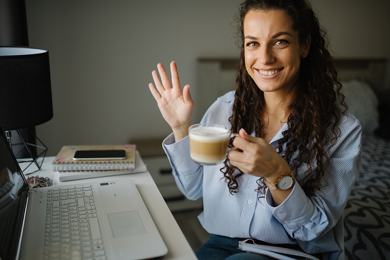 Woman enjoying coffee while working on a laptop in a cozy space
