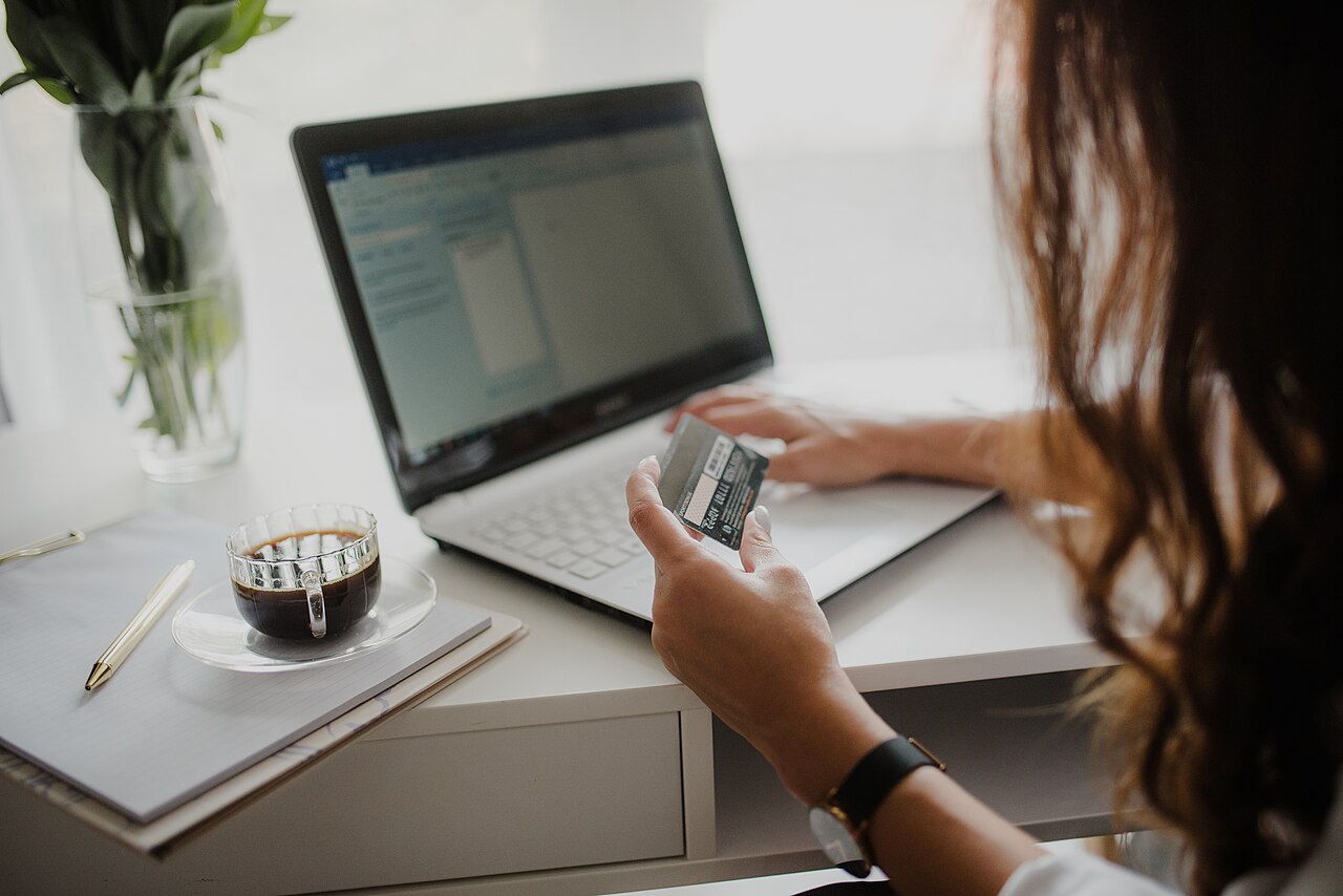 Close-up of a woman looking at a credit card while working on her laptop