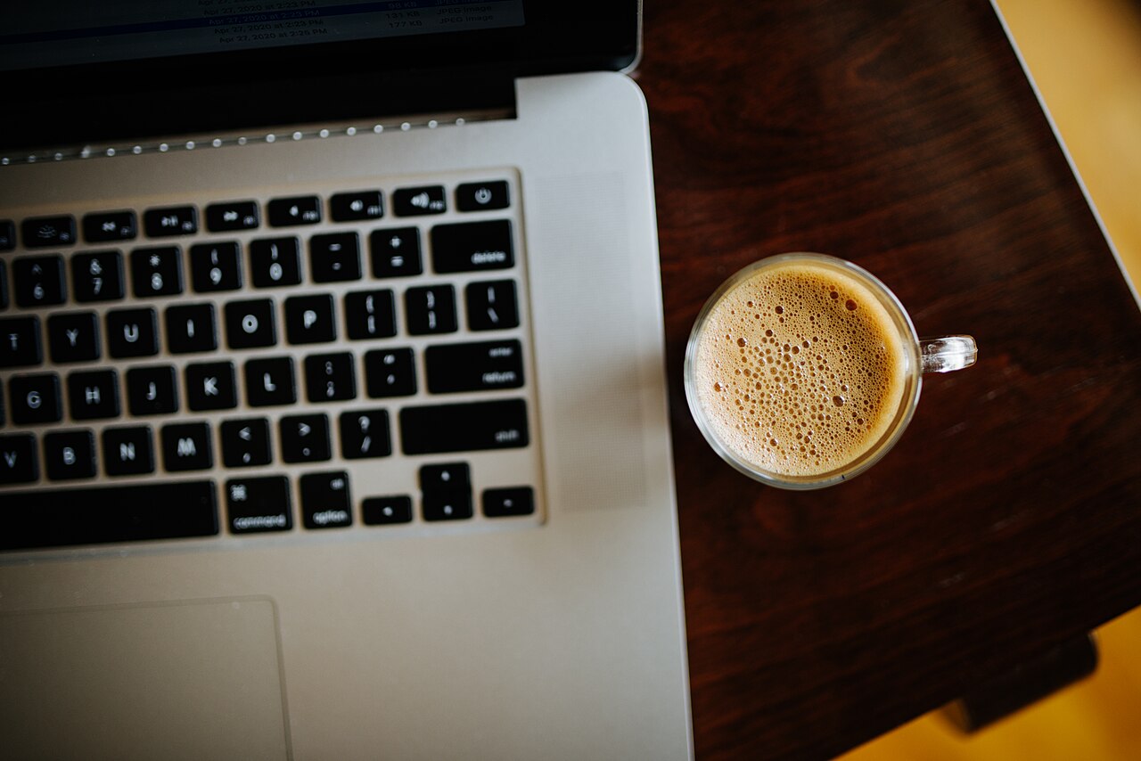 A coffee cup next to a laptop on a wooden table in a cozy workspace