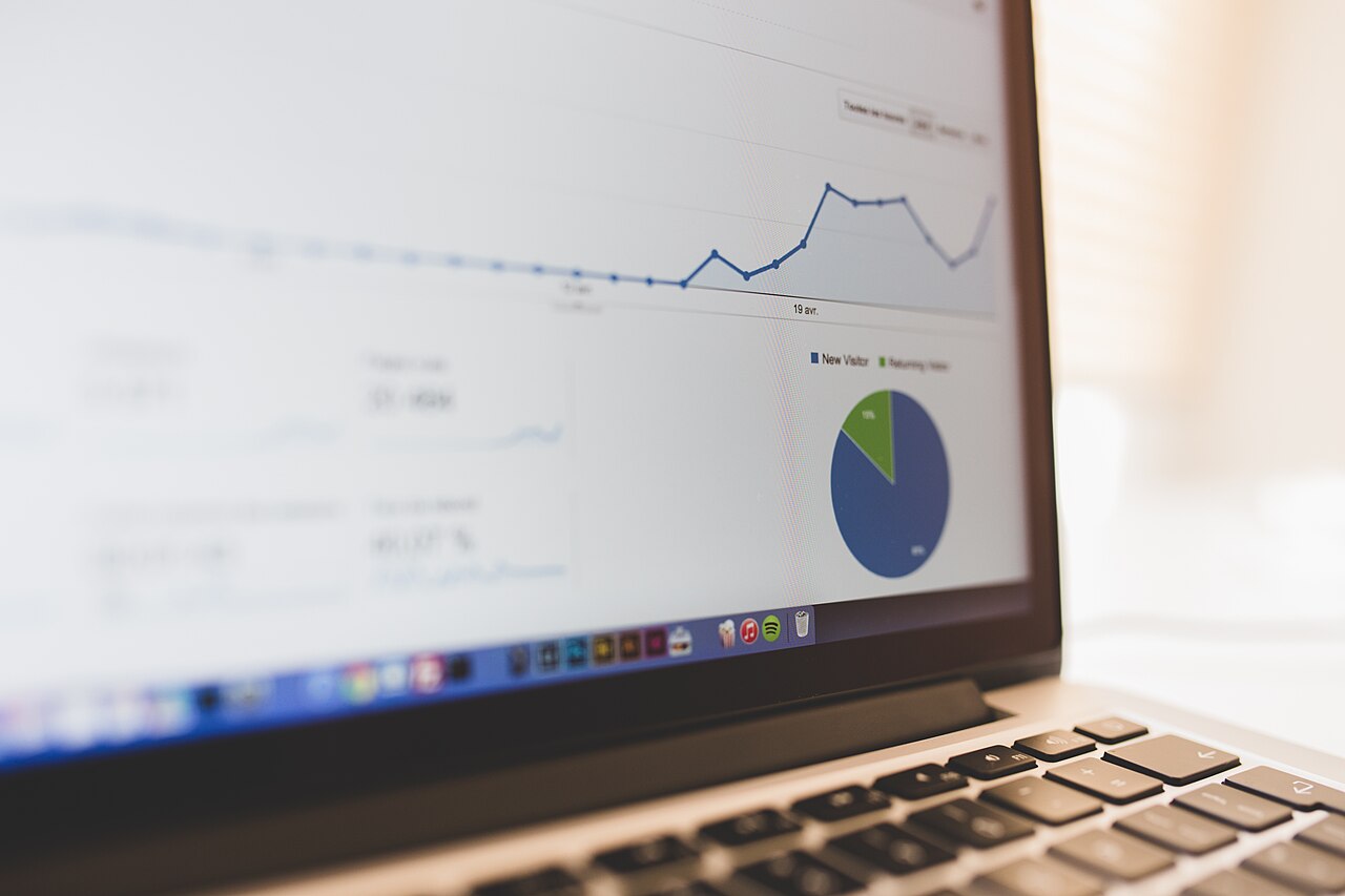 Laptop screen showing website analytics charts with a line graph and a visitor pie chart